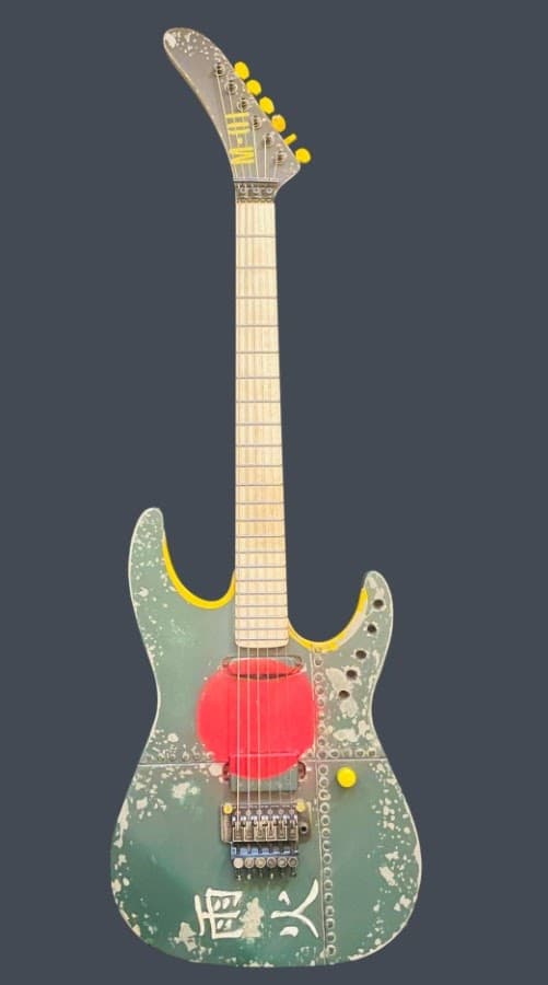 Electric guitar with a distressed green paint job, a red circle graphic, yellow accents, and kanji lettering near the base.